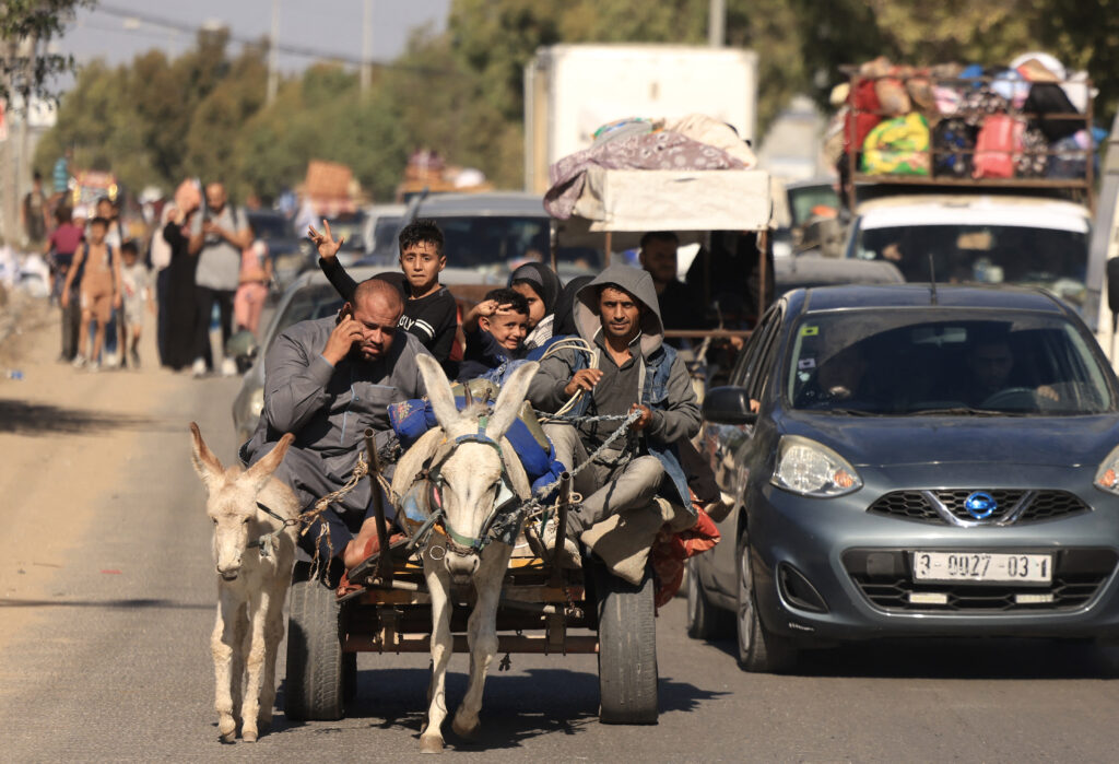 Riding a donkey drawn cart as family along with hundreds of other Palestinian carrying their belongings flee following the Israeli army's warning to leave their homes and move south before an expected ground offensive, in Gaza City on October 13, 2023. Palestinians carried belongings through the rubble-strewn streets of Gaza City on October 13, in search of refuge as Israel's army warned residents to flee immediately before an expected ground offensive in retaliation against Hamas for the deadliest attack in Israeli history. (Photo by MAHMUD HAMS / AFP)