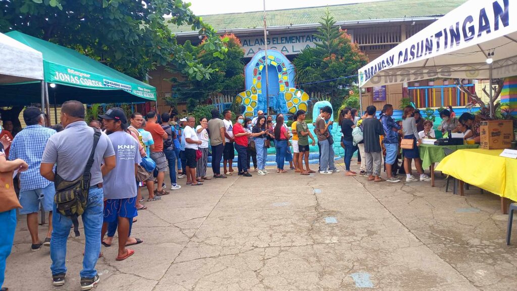 Voters at the Cabancalan 1 Elementary School get their precinct number at the Voters Assistance Desk at 8 a.m. today to cast their votes.