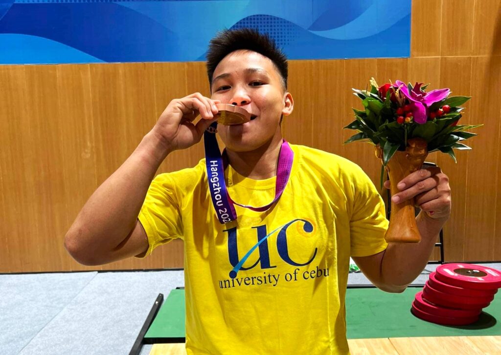 UC athletic chief on Ando's bronze finish in Asiad: It felt like a gold medal win. In photo is Elreen Ando biting her bronze medal which she earned in the Asian Games women's weightlifting event. | Photo from Ando's Facebook page
