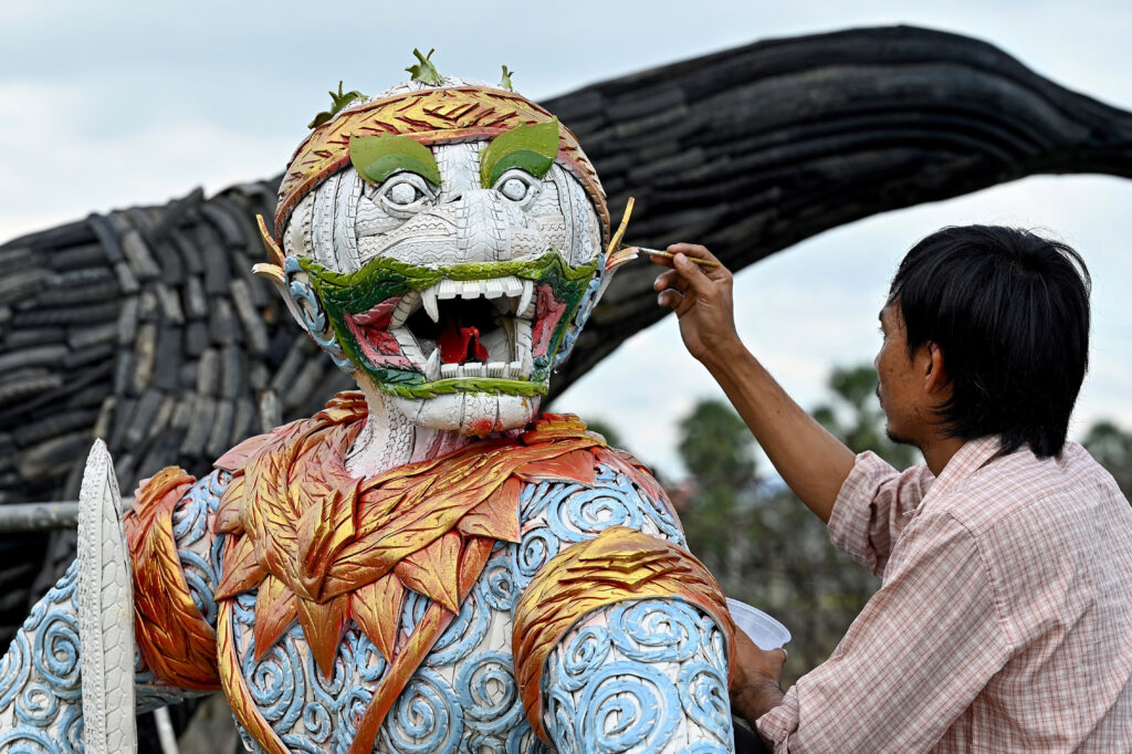 This photo taken on November 7, 2023 shows artist Mean Tithpheap painting a Monkey King statue made with motorbike and bicycle tyres at his house in Kandal province. Cambodian artist Mean Tithpheap has made some 40 statues for clients including King Kongs, elephants, lions, cobras, using bicycle and motorbike tyres with the hope of encouraging others to reuse materials in their work. (Photo by TANG CHHIN Sothy / AFP)