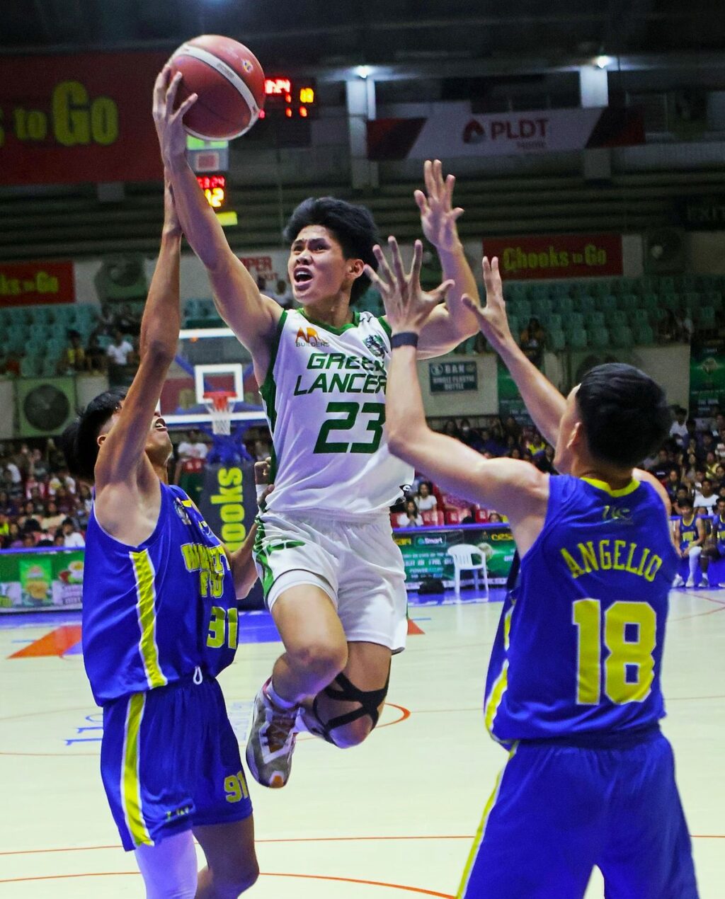 Raul Gentallan of the UV Green Lancers soars high between two UC Webmasters defenders during their game in the Cesafi men's basketball.