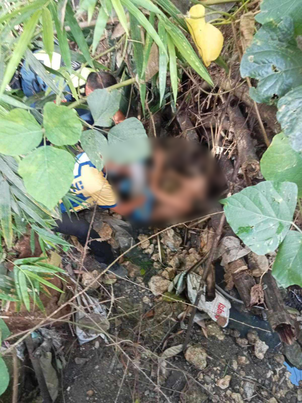 A suspected robber, with a broken leg, lies helplessly at the riverbank as police approach to arrest him in Tuscania Garden, Barangay Guadalupe, Cebu City this morning, November 6, 2023. | Contributed photo 