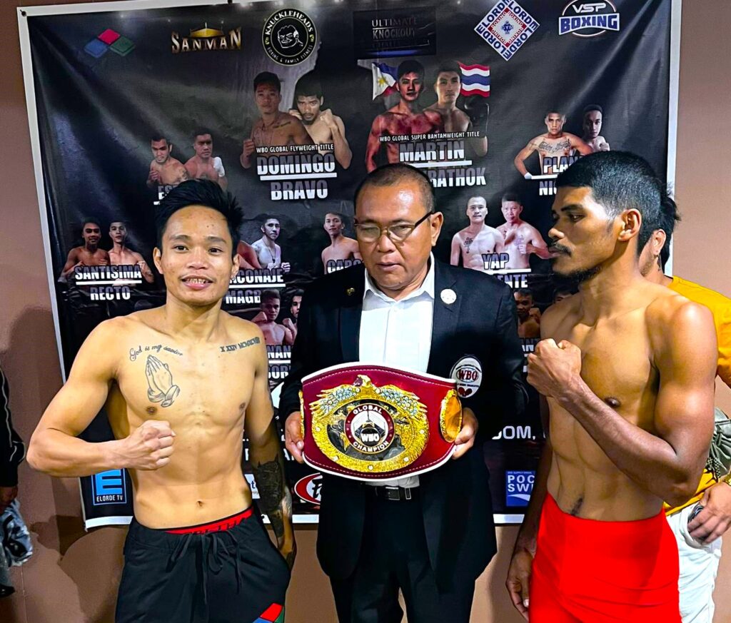 Esneth Domingo (left) and Michael Bravo (right) pose for the camera after passing the weigh-in for their WBO Global flyweight title bout in Manila. Holding the title is WBO international judge Edward Ligas of Cebu.
