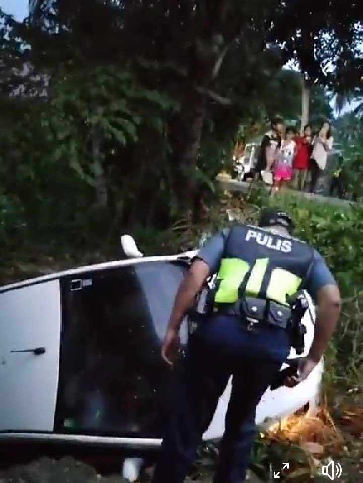 A policeman checks on the passenger of the car which fell off a 3-meter deep ravine in Asturias town on Sunday, December 17. | Contributed photo via Paul Lauro