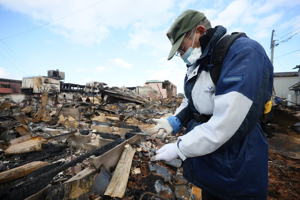 A man finds his wife's sewing scissors at their home which was destroyed by fire in the city of Wajima, Ishikawa prefecture on January 4, 2024, after a major 7.5 magnitude earthquake struck the Noto region in Ishikawa prefecture on New Year's Day. | AFP