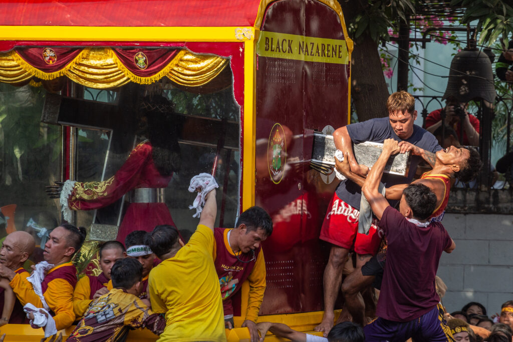 Catholic devotees touch the end of the cross of the Black Nazarene during the annual religious procession in Manila on January 9, 2024. | AFP