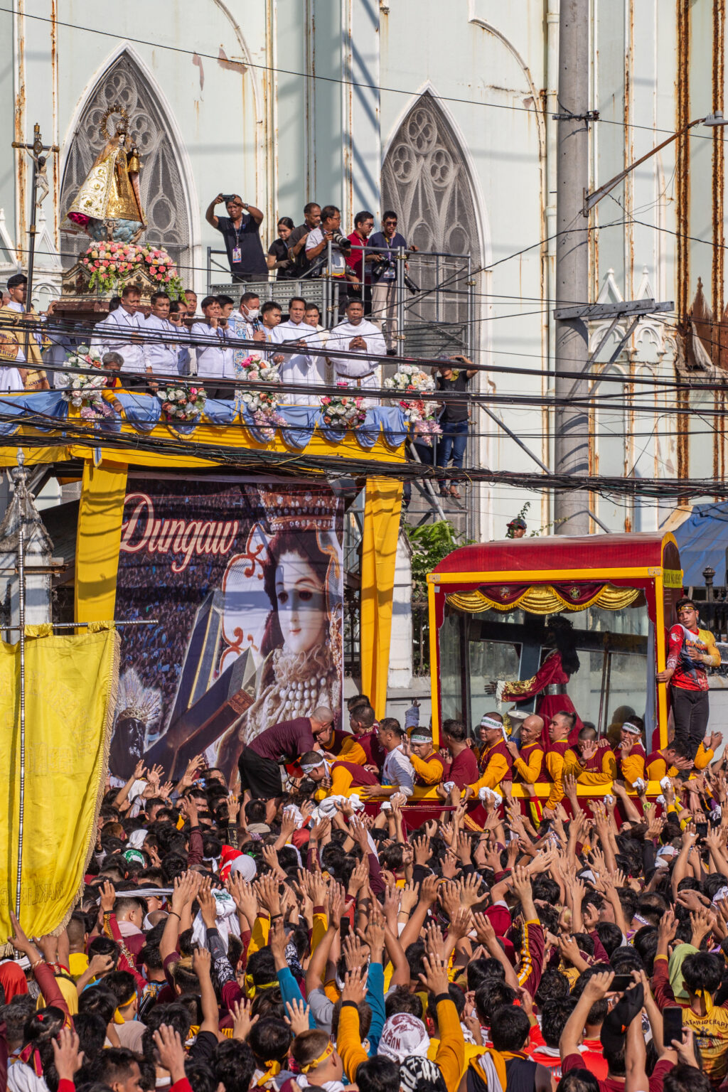 Catholic devotees pray as the glass-covered carriage of the Black Nazarene stop in front of the image of Our Lady of Mount Carmel for the traditional "dungaw" during the annual religious procession in Manila on January 9, 2024. | AFP