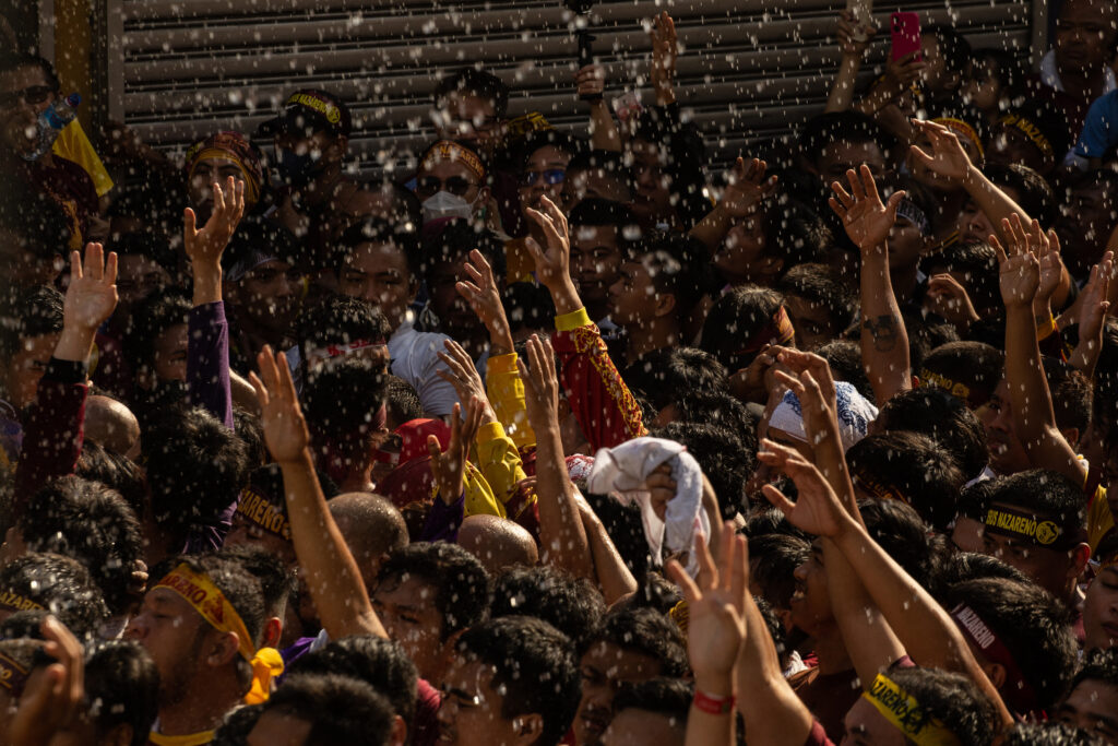 Traslacion: Catholic devotees ask other devotees for water as they jostle with each other during the annual religious procession of the Black Nazarene in Manila on January 9, 2024. | AFP