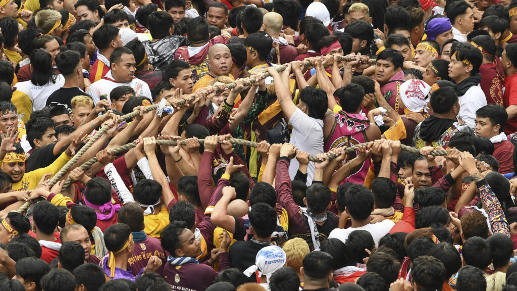 Traslacion: Catholic devotees hold the rope attached to a glass-covered carriage carrying the Black Nazarene statue during an annual religious procession in Manila on January 9, 2024. | AFP