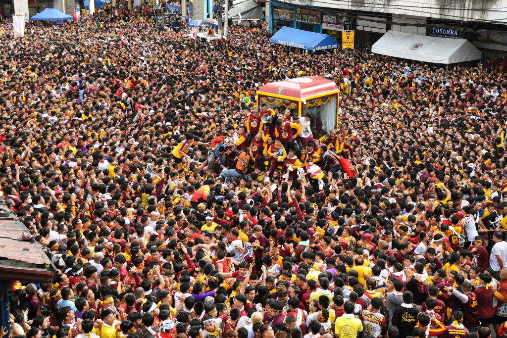 Traslacion: Catholic devotees jostle with each other as they try to touch a glass-covered carriage carrying the image of Black Nazarene during an annual religious procession in Manila on January 9, 2024. |Photo by Ted ALJIBE / AFP)