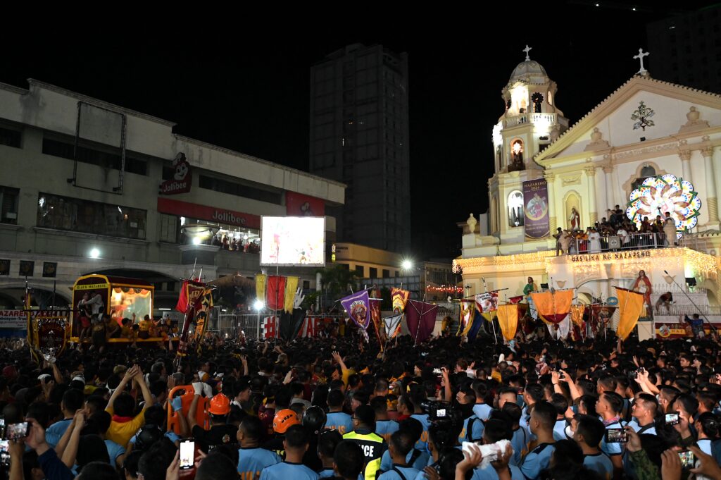 Catholic devotees jostle with each other as the glass-covered carriage carrying the so-called Black Nazarene approaches the Quiapo Church during an annual religious procession in Manila on January 9, 2024. |AFP