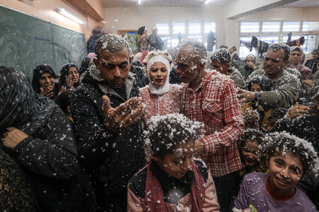 Palestinian newly-weds Afnan Jibril (C) and her groom are surrounded by guests and relatives their wedding at the UNRWA School in the al-Salam neighborhood of Rafah, southern Gaza Strip, on January 12, 2024, amid continuing battles between Israel and the militant group Hamas. | AFP