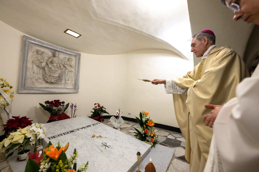 Pope recalls Benedict XVI's love and wisdom on anniversary of death. In photo is former Pope Benedict's closest aide and private secretary, Archbishop Georg Ganswein, praying over the the tomb of Pope Emeritus in St. Peter's Basilica, at the Vatican, December 31, 2023.    Vatican Media/­Handout via REUTERS