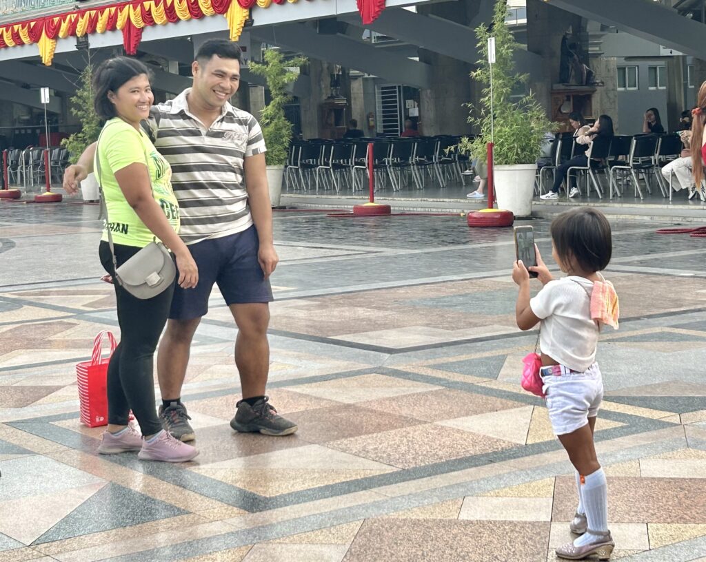 Sinulog Festival: Of families and their practices paying homage to Sto. Niño. In phot is a little girl taking a picture of her parents at the Basilica. 