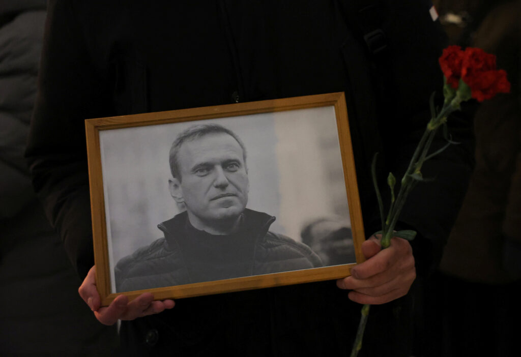Navalny death: A person holds flowers and a portrait of Russian opposition leader Alexei Navalny at the monument to the victims of political repressions following Navalny's death, in Saint Petersburg, Russia February 16, 2024. REUTERS/Stringer
