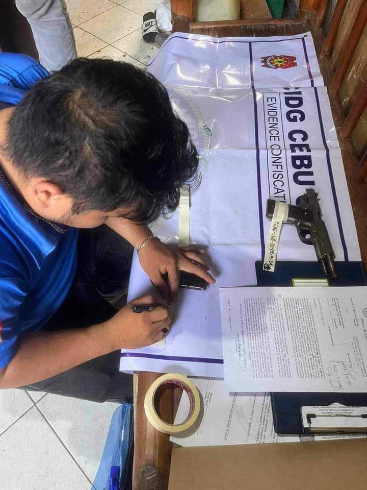 A police officer of the CIDG Cebu City Field Office processes the pieces of evidence against a man caught with an unlicensed pistol and ammunition. | Contributed photo via Paul Lauro