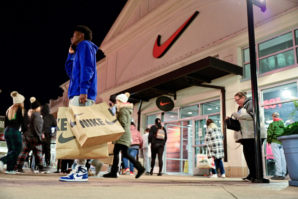 For Nike, ‘it’s gotta be the shoes’ is a thing of the past.A man with Nike bags talks on the phone in front of a Nike store as Black Friday sales begin at The Outlet Shoppes of the Bluegrass in Simpsonville, Kentucky, U.S., November 26, 2021. REUTERS/Jon Cherry/File Photo