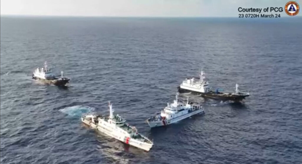 PH warned by China: Prepare to ‘bear consequences’ in South China Sea. SURROUNDED This frame grab from aerial video footage taken and released on March 23 by the Philippine Coast Guard (PCG) shows a China Coast Guard ship and vessels identified by PCGas “Chinese Maritime Militia” (left and right) surrounding the PCG ship BRP Cabra during its supply mission near Ayungin (Second Thomas) Shoal in theWest Philippine Sea. —AFP/PCG