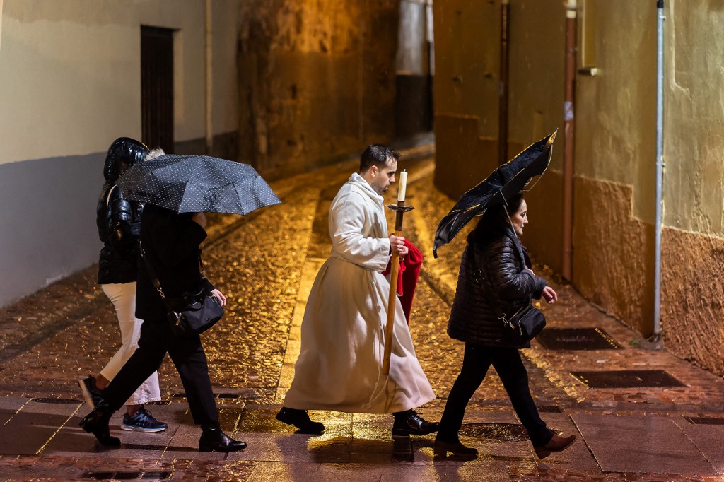 A penitent from the ‘Real Hermandad del Santisimo Cristo de las Injurias, Cofradia del Silencio’ brotherhood walks along the street after his procession was suspended due to the rain.
