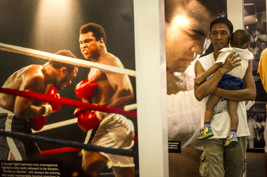 Shoppers look at memorabilia and photo exhibit featuring Muhammad Ali at the Ali Mall in Manila on June 10, 2016. | AFP