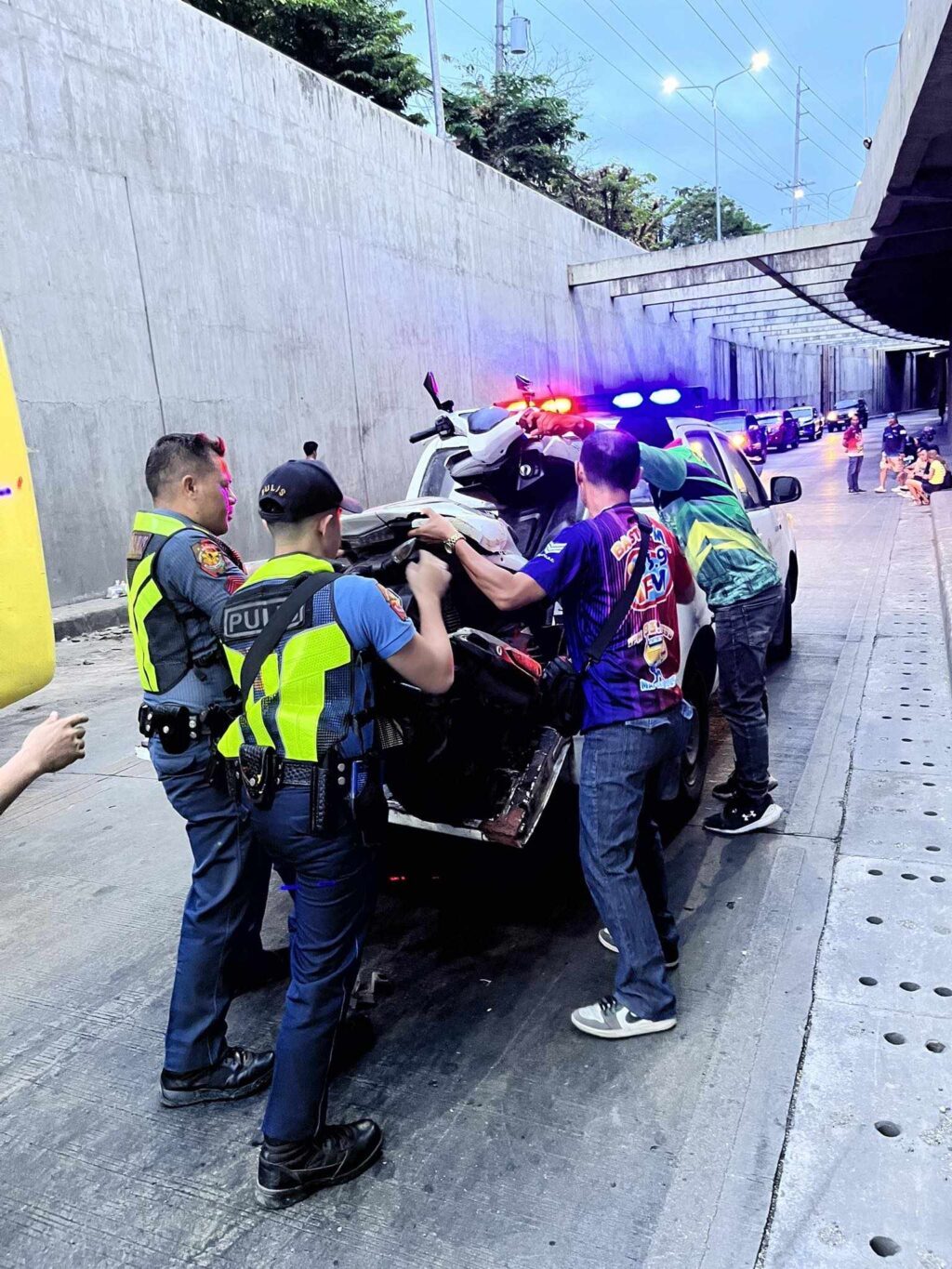 Traffic policemen and traffic enforcers place the motorcycle involved in the collision with a bus in the Mambaling Underpass on a pickup to be brought to the police station. | Contributed photo via Paul Lauro