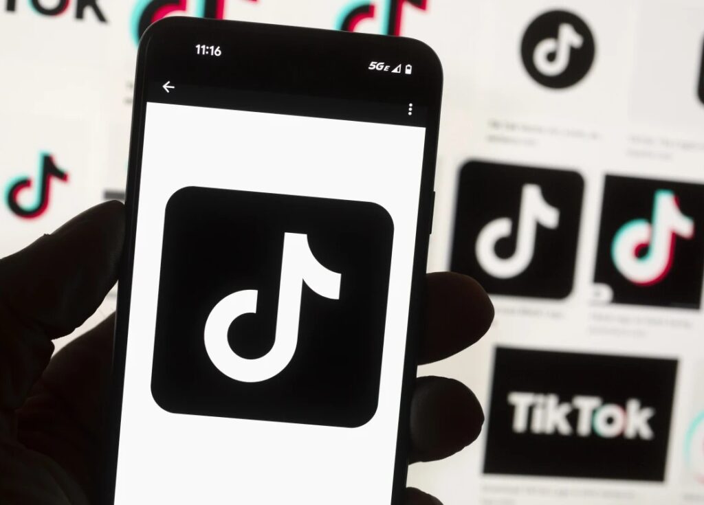 The TikTok logo is displayed on a mobilephone in front of a computer screen, Oct. 14, 2022, in Boston. TikTok is gearing up for a legal fight against a U.S. law that would force the social media platform to break ties with its China-based parent company or face a ban. A battle in the courts will almost certainly be backed by Chinese authorities as the bitter U.S.-China rivalry threatens the future of a wildly popular way for young Americans to connect online.