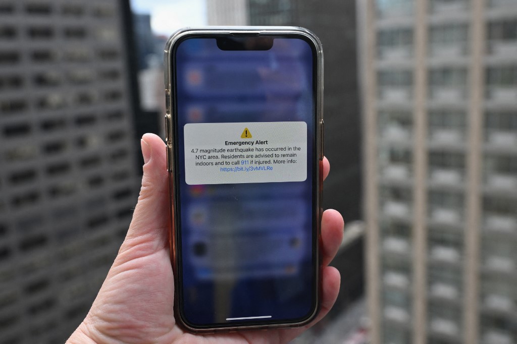 In this illustration, a phone shows an Emergency Alert message on April 5, 2024, warning of an earthquake in New York. 
