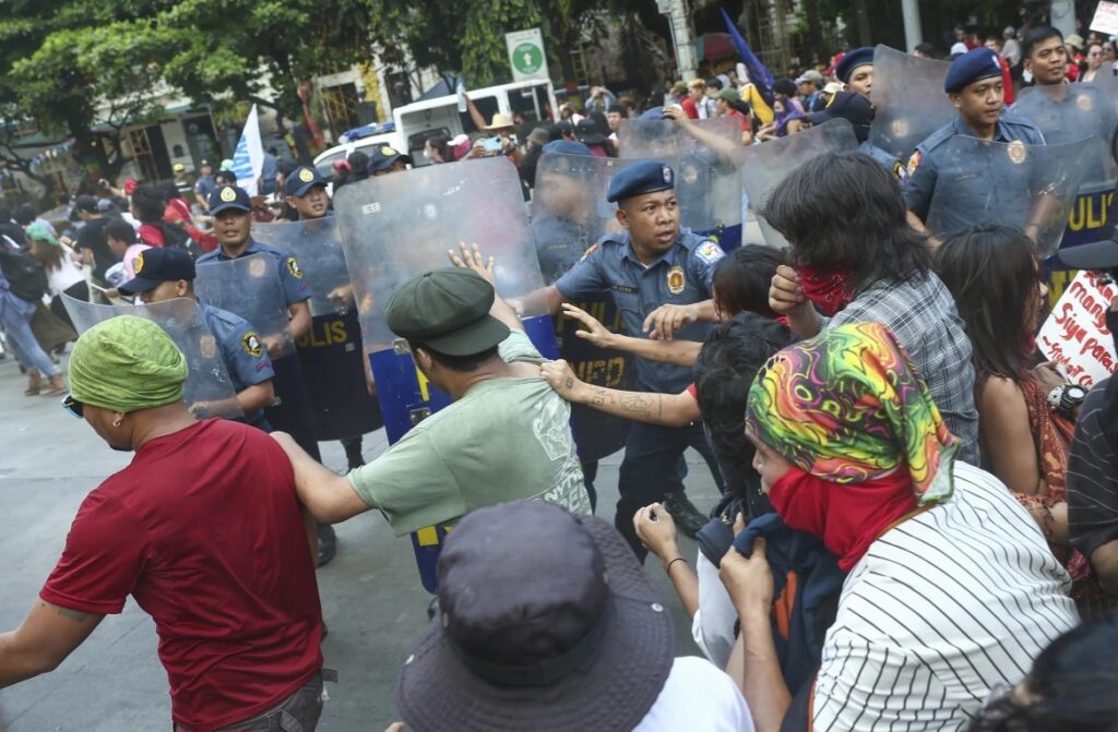 Policemen try to block activists as they try to march towards the U.S. Embassy during a protest to mark International Labor Day, in Manila, Philippines, Wednesday, May 1, 2024.
