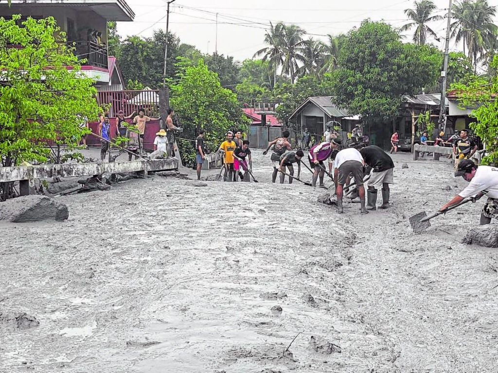 Residents of Barangay Biak na Bato in La Castellana, Negros Occidental, on Wednesday work together to clear lahar that covered the village’s roads and blocked the flow of traffic. Lahar flowed through the village’s streams and rivers after rains washed down ash and debris from Mt. Kanlaon’s eruption on Monday night. (CONTRIBUTED PHOTO)