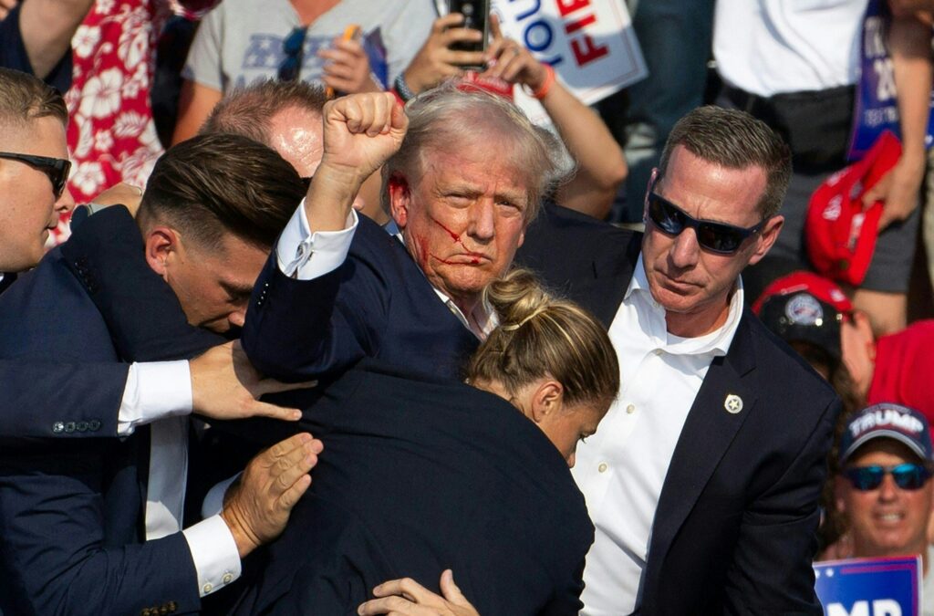 Trump rally shooting reshapes US election. Republican candidate Donald Trump is seen with blood on his face surrounded by secret service agents as he is taken off the stage at a campaign event at Butler Farm Show Inc. in Butler, Pennsylvania, July 13, 2024. Donald Trump was hit in the ear in an apparent assassination attempt by a gunman at a campaign rally on Saturday, in a chaotic and shocking incident that will fuel fears of instability ahead of the 2024 US presidential election. | AFP