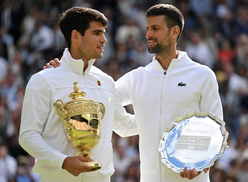 Spain's Carlos Alcaraz holding the winner's trophy (L) is congratulated by Serbia's Novak Djokovic as they pose for pictures during the price ceremony at the end of their men's singles final tennis match on the fourteenth day of the 2024 Wimbledon Championships at The All England Lawn Tennis and Croquet Club in Wimbledon, southwest London, on July 14, 2024.| AFP