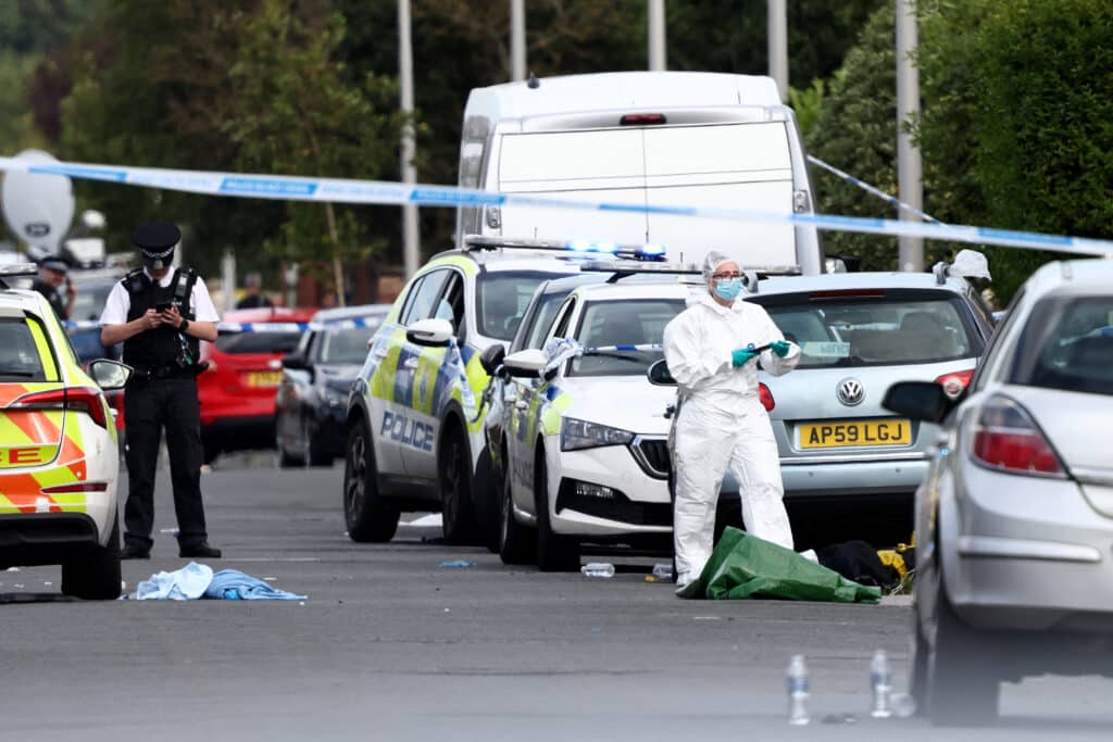 UK knife attack: Bloodied children seen fleeing community center. Police officers and forensic personnel stand behind a cordon on Hart Street in Southport, northwest England, on July 29, 2024, following a knife attack. A suspected knife attack in northern England left at least eight people injured, believed to include children, emergency services said. (Photo by Darren Staples / AFP)