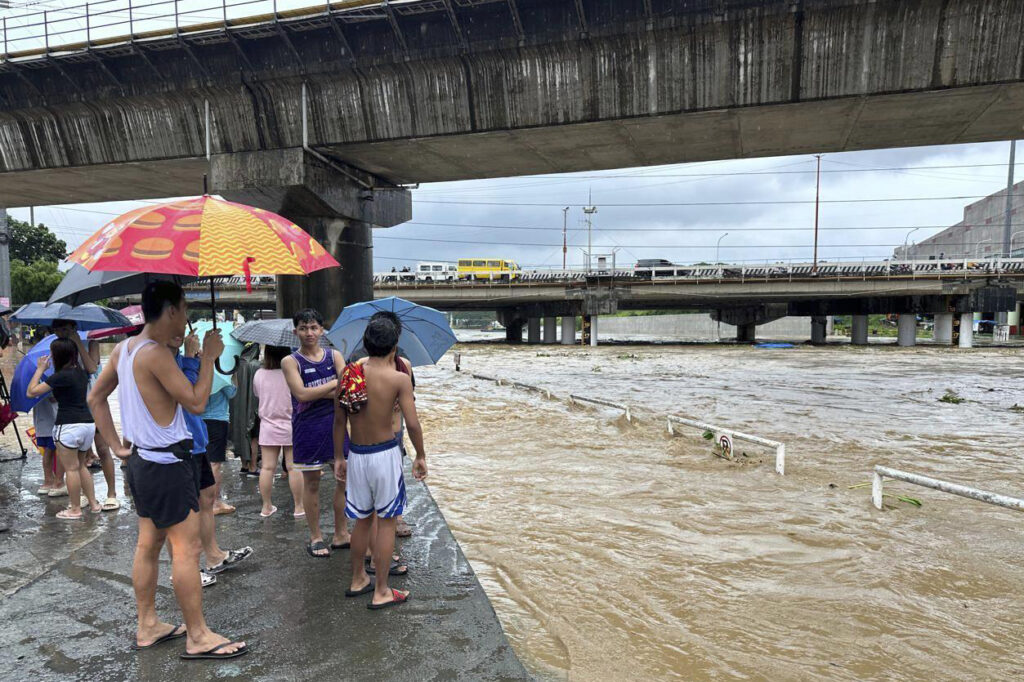 Residents watch the Marikina river as it floods from monsoon rains worsened by offshore typhoon Gaemi on Wednesday, July 24, 2024, near Manila, Philippines. (AP Photo/Joeal Capulitan)