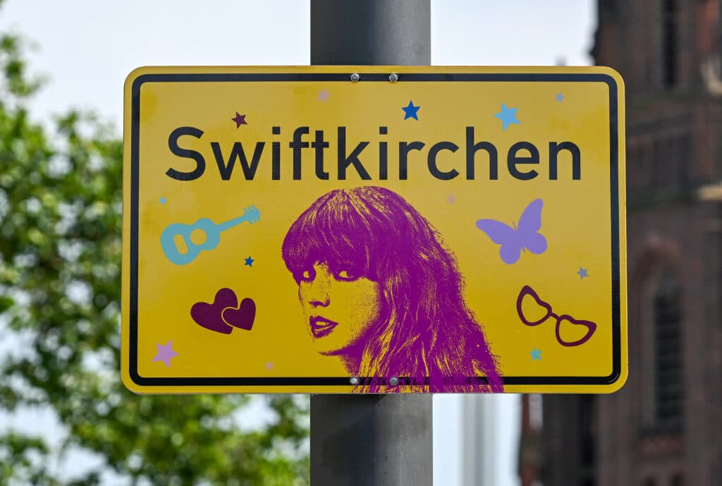 Swiftkirchen signs: Renamed German City for Swift concerts gets bids. A newly designed city sign with the lettering 'Swiftkirchen' is seen in Gelsenkirchen, western Germany on July 17, 2024, prior to the first of three concerts that US musician and pop icon Taylor Swift will perform at the Veltins Arena as part of her 'Eras Tour'. Swift's concerts with take place on July 17, 18 and 19, 2024. (Photo by Ina FASSBENDER / AFP)