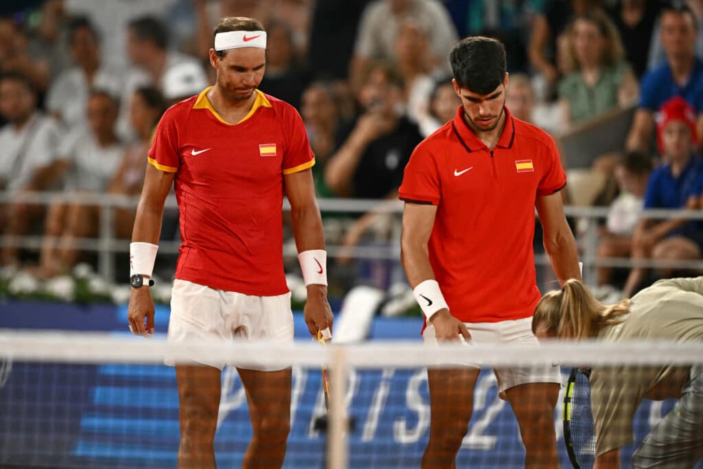 Spain's Rafael Nadal (L) and Spain's Carlos Alcaraz (R) check the final line call with chair umpire Miriam Bley (R) as they lose against US' Austin Krajicek and US' Rajeev Ram in their men's doubles quarter-final tennis match on Court Philippe-Chatrier at the Roland-Garros Stadium. |AFP