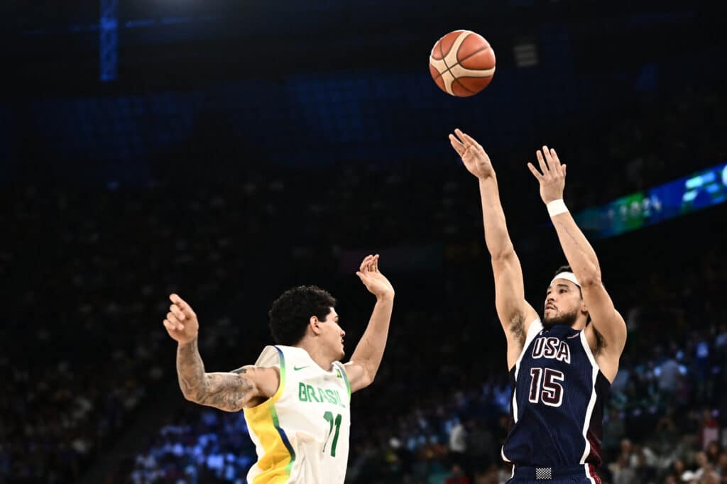 Paris Olympics: US routs Brazil to reach basketball semis. USA's #15 Devin Booker takes a shot past Brazil's #11 Gui Santos in the men's quarterfinal basketball match between Brazil and the USA during the Paris 2024 Olympic Games at the Bercy  Arena in Paris on August 6, 2024. (Photo by Aris MESSINIS / AFP)