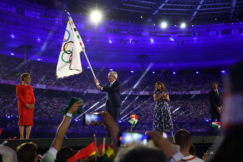 International Olympic Committee (IOC) President Thomas Bach (C) hands over the Olympic flag to Los Angeles' Mayor Karen Bass (L) next to Paris' Mayor Anne Hidalgo (R) during the closing ceremony of the Paris 2024 Olympic Games at the Stade de France, in Saint-Denis, in the outskirts of Paris, on August 11, 2024. | Photo by Franck FIFE / AFP