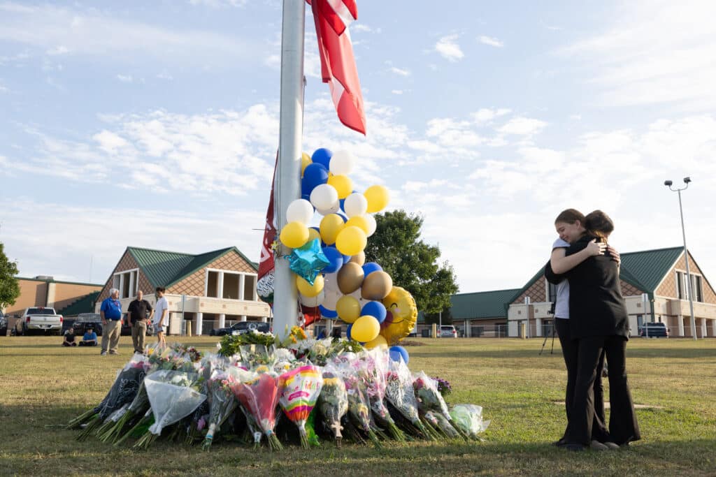 US school shooting: Father of 14-year-old suspect arrested. In photo are students embracing near a makeshift memorial for those who died in the shooting done by a 14-year-old student at Apalachee High School on September 5, 2024 in Winder, Georgia. | Jessica McGowan/Getty Images/AFP