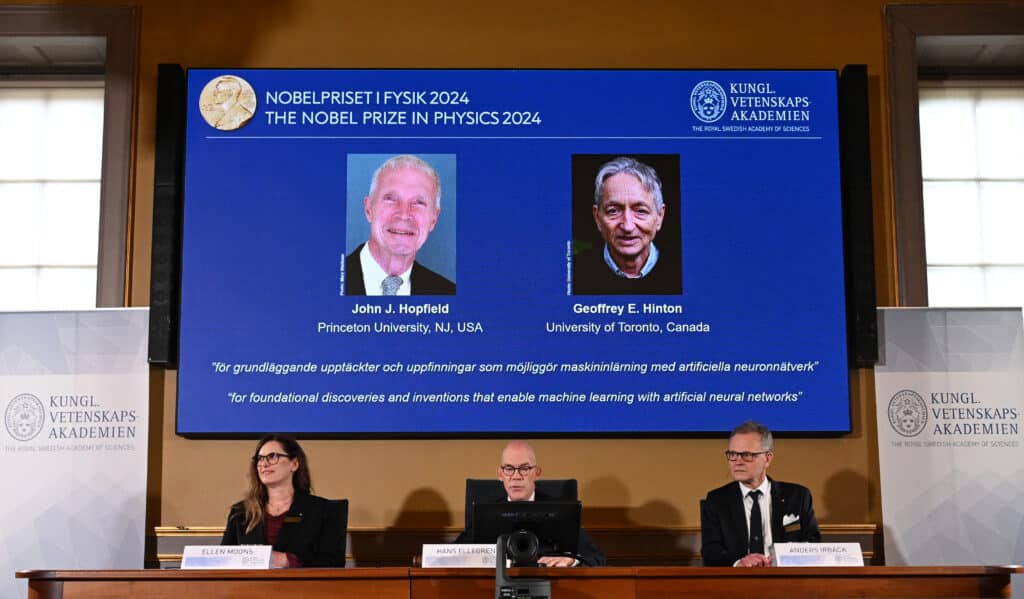 A screen shows the laureates of the 2024 Nobel Prize in Physics, US physicist John J Hopfield (top left) and Canadian-British computer scientist and cognitive psychologist Geoffrey E Hinton as Chair of the Nobel Committee for Physics Ellen Moons (bottom, sitting, from left), Secretary General of the Royal Swedish Academy of Sciences Hans Ellegren and Member of the Nobel Committee for Physics Anders Irbaeck make the announcement at the Royal Swedish Academy of Sciences in Stockholm, Sweden on October 8, 2024. |Photo by Jonathan NACKSTRAND / AFP