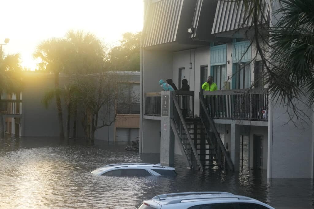 Hurricane Milton tornadoes kill 4 in Florida amid rescue efforts. Residents look on from a balcony as floods due to Hurricane Milton on October 10, 2024 in Clearwater, Florida submerge cars in the area. | Photo by Bryan R. SMITH / AFP