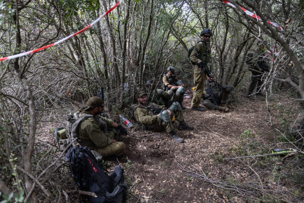 This picture taken on October 13, 2024, shows Israeli soldiers resting near what they said is an abandoned Hezbollah position, during a controlled embed organised by the Israeli military in southern Lebanon's Naqoura region near the border with Israel. | Photo by Menahem KAHANA / AFP