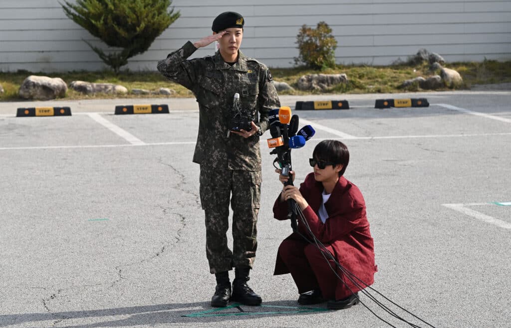 BTS member J-hope (left) salutes while fellow member Jin (right) holds microphones. This was after being discharged from his mandatory military service outside a military base in Wonju on October 17, 2024. | Photo by JUNG YEON-JE / AFP