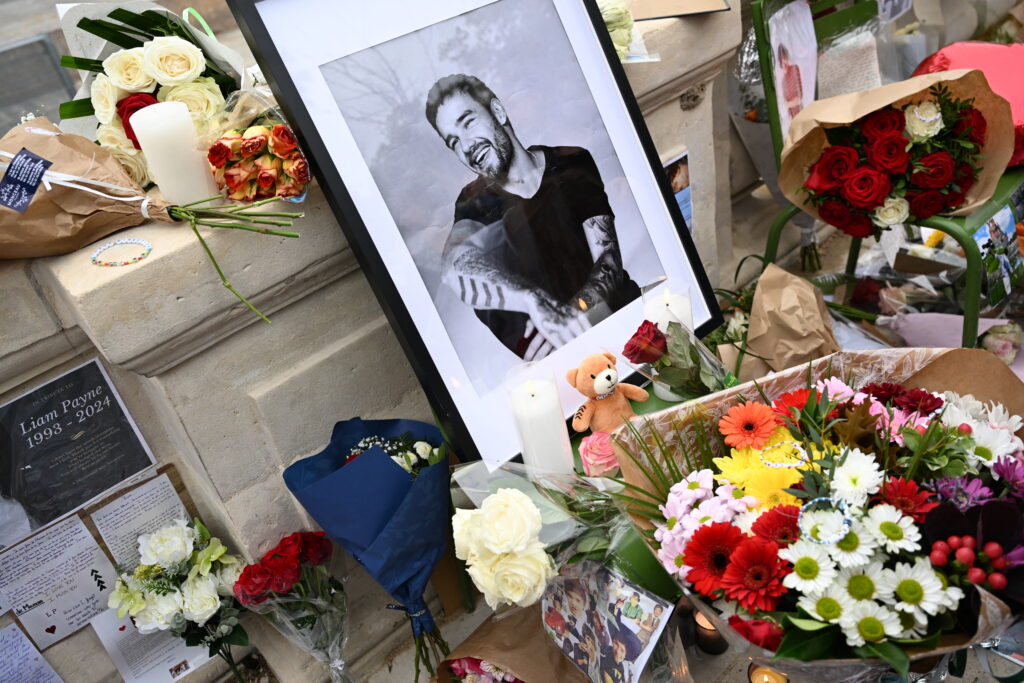 This photograph shows displayed flowers and a framed picture of late British singer Liam Payne as fans gather to pay tribute to the former member of the British pop band One Direction, at Jardin des Tuileries in Paris, on October 20, 2024. (Photo by Bertrand GUAY / AFP)