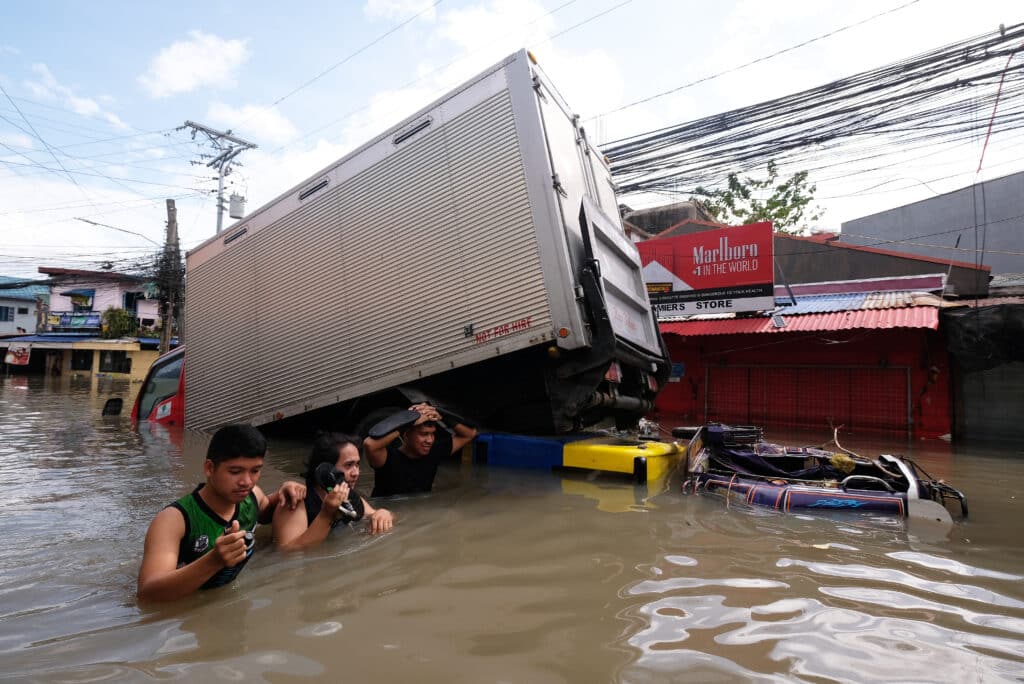 People wade through a flooded road brought about by Tropical Storm Trami, in Naga, Camarines Sur on October 25, 2024. | Photo by ZALRIAN SAYAT / AFP