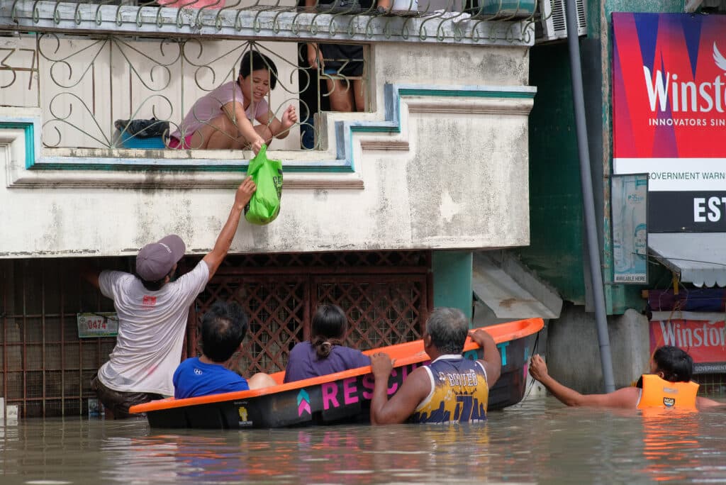 People on a boat conduct relief operations at a flooded area due to the heavy rains brought about by Tropical Storm Trami in Naga, Camarines Sur on October 25, 2024. | Photo by ZALRIAN SAYAT / AFP