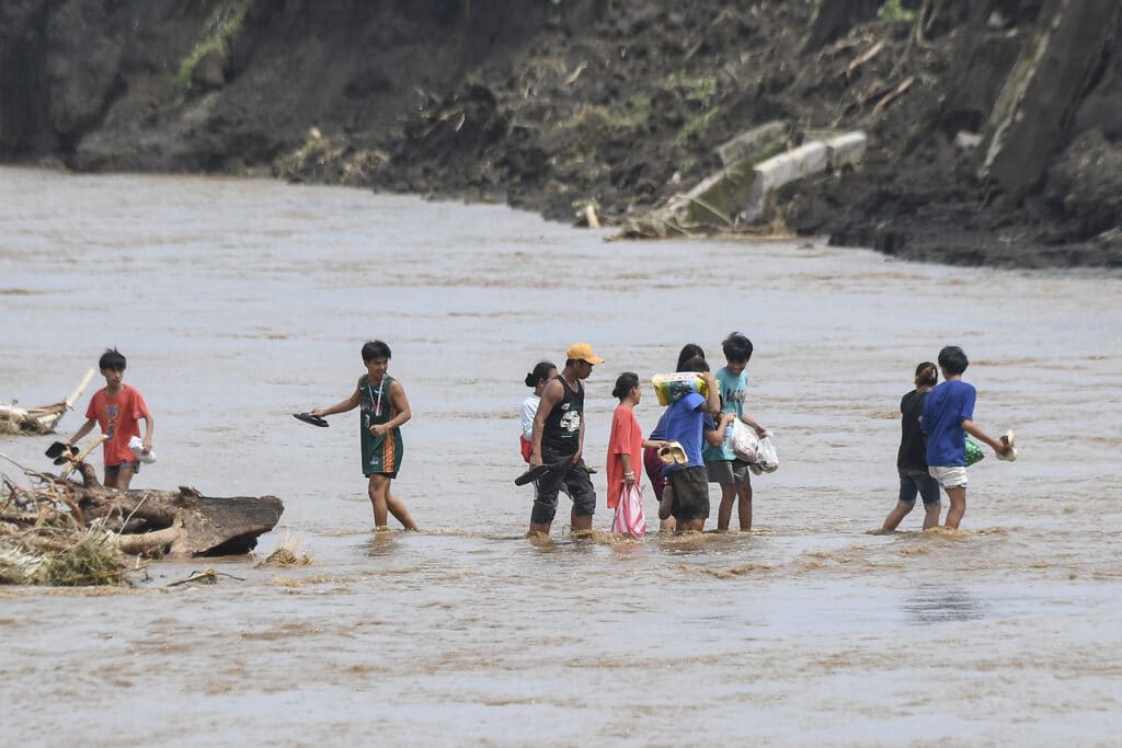 Kristine: Floods submerge towns, death toll rises to 66. In photo are people crossing a river next to a bridge that collapsed after the river overflew due to heavy rains brought about by Tropical Storm Trami in Laurel, Batangas province, south of Manila on October 25, 2024.| Photo by Ted ALJIBE / AFP