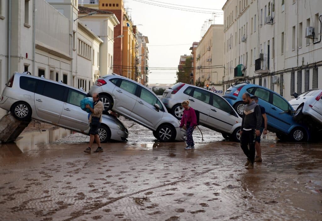 Residents walk past piled up cars following deadly floods in Valencia's De La Torre neighbourhood, south of Valencia, eastern Spain, on October 30, 2024. | Photo by Manaure QUINTERO / AFP