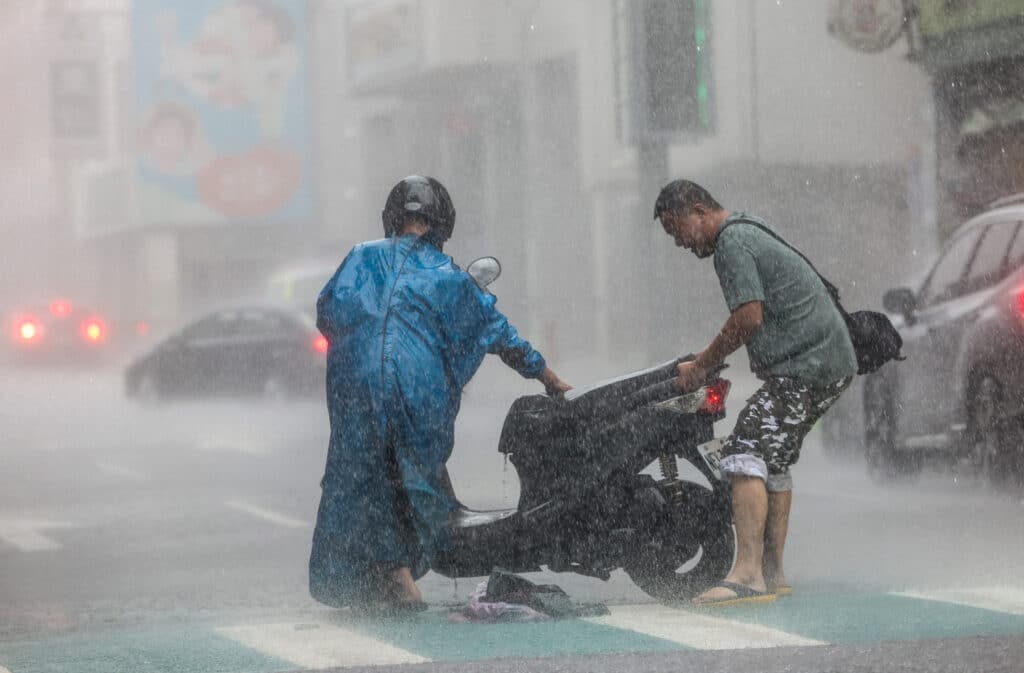 Super Typhoon Kong-Rey nears Taiwan, offices, schools closed. A man (R) helps a motorist with a scooter amid heavy rain due to Super Typhoon Kong-rey in Keelung on October 31, 2024. | Photo by I-Hwa CHENG / AFP