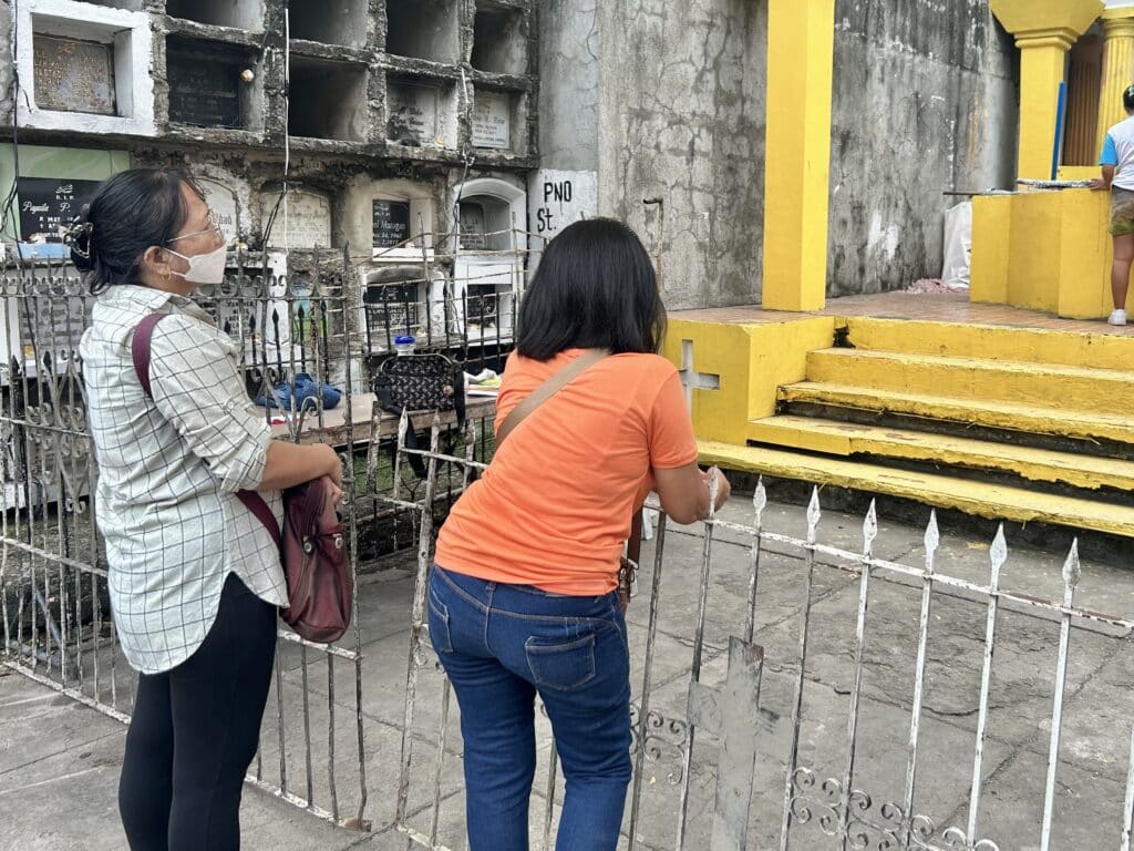 A few individuals visited the common grave and light candles days before the celebration of All Souls’ Day 2024. CDN Digital Photo | Emmariel Ares