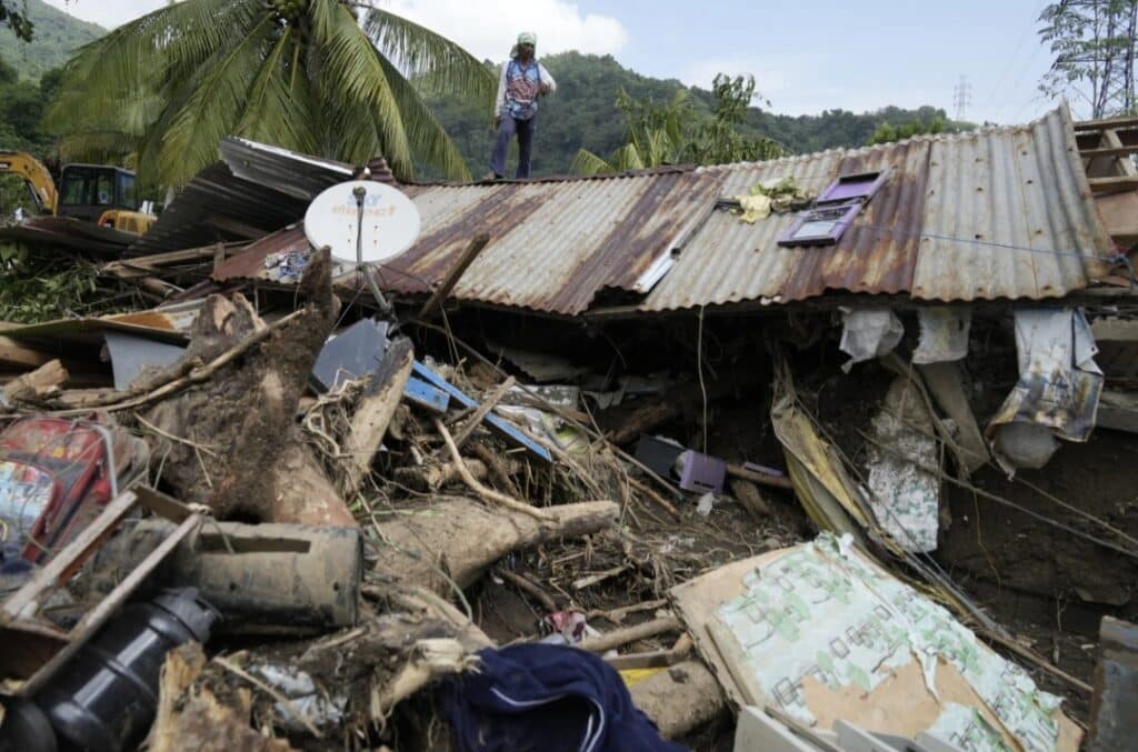 Marcelino Aringo stands on top of a damaged house after a landslide triggered by Tropical Storm Trami recently struck Talisay, Batangas province, Philippines, Saturday, Oct. 26, 2024